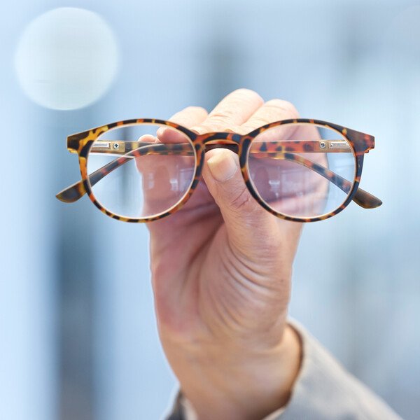 Optiker hält Brille zur Anpassung - professionelle Brillenberatung