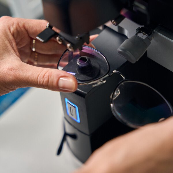 Optiker justiert Brille im Messgerät - präzise Brillenanpassung
