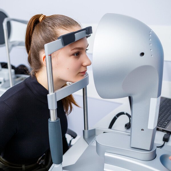 Augenoptiker bei der Sehstärkenbestimmung mit Messbrille